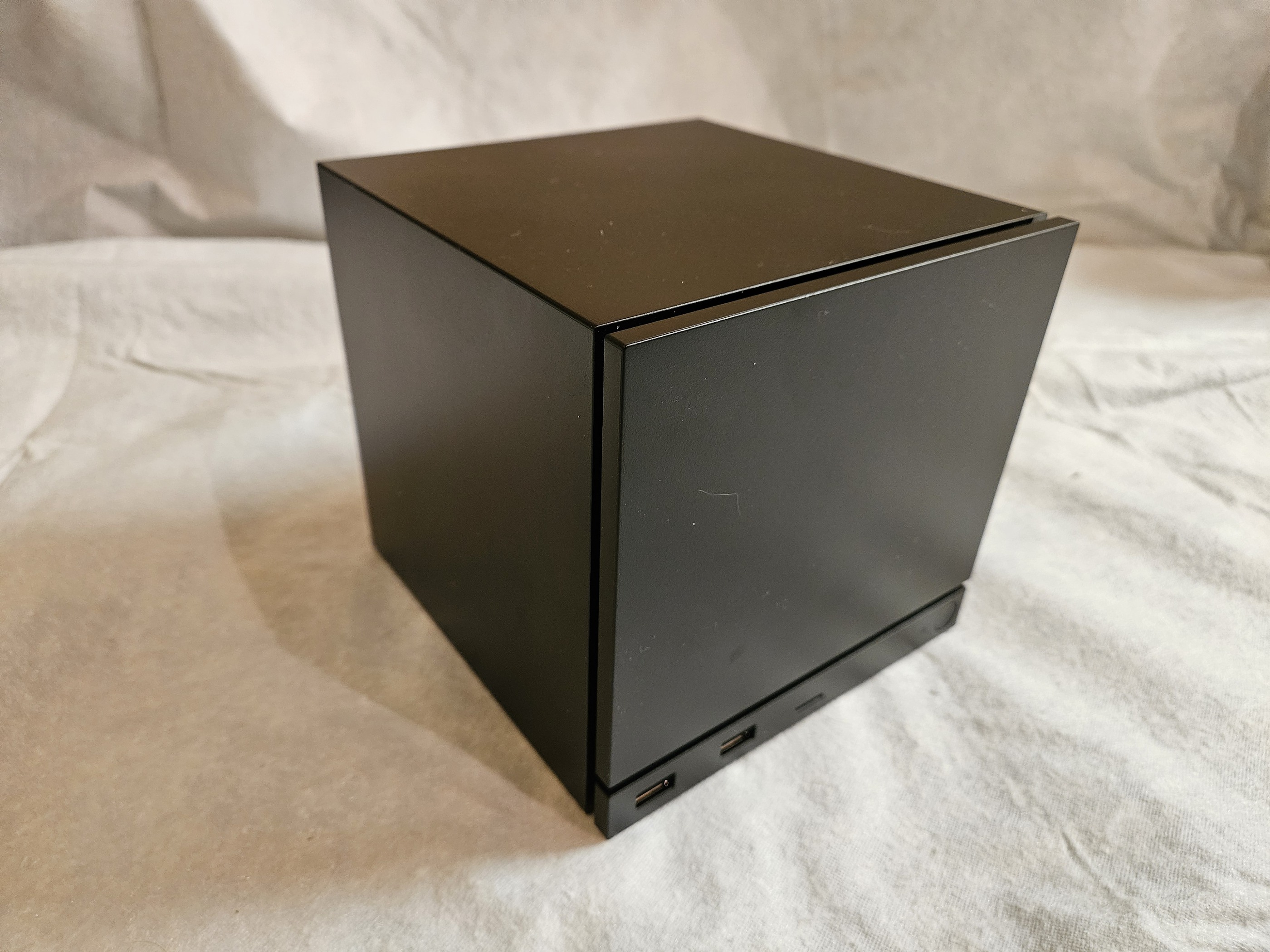 Valve Steam Machine cube from the front on a fabric surface